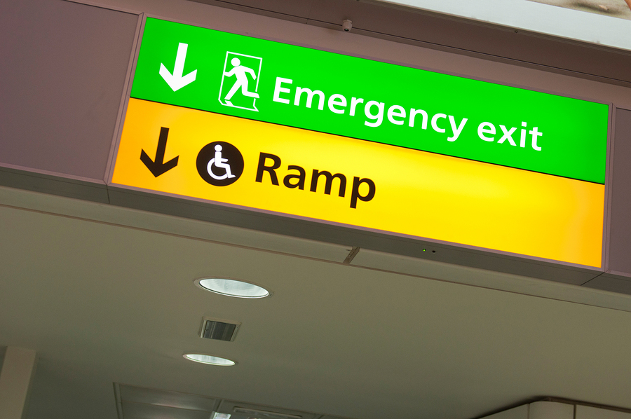 An emergency exit sign and an indicator for a wheelchair-accessible ramp.